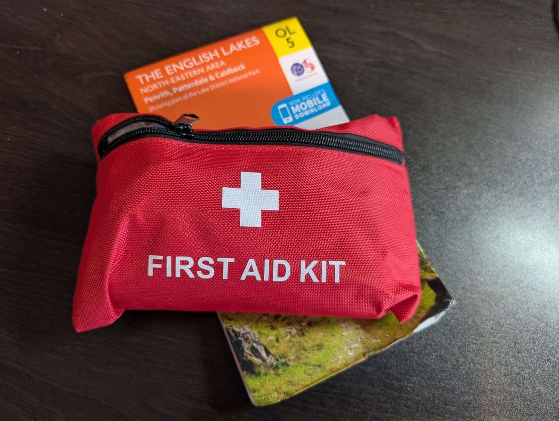 A compact red first-aid kit pouch resting on an OS Explorer OL5 map of the north-eastern Lake District.
