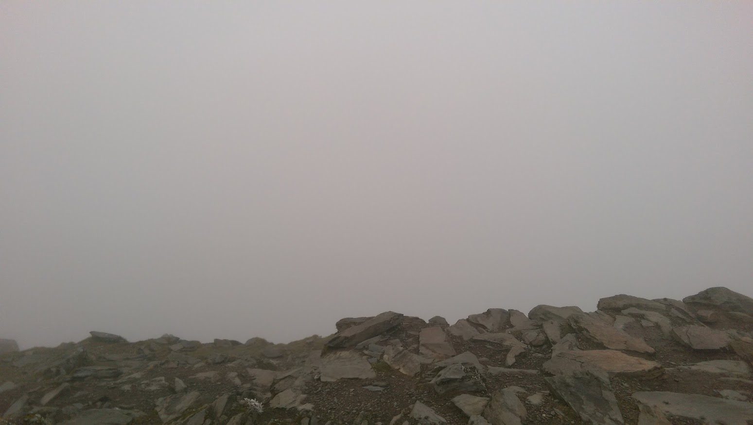 Thick cloud sitting down on a Lake District fell, the path ahead vanishing into grey with visibility down to a few metres.