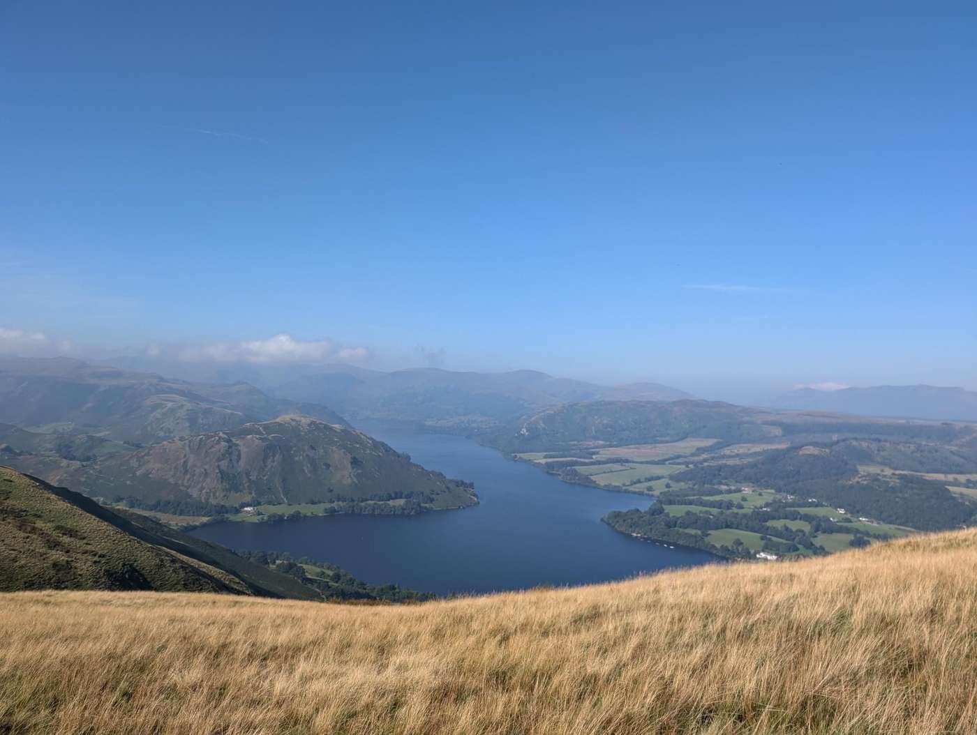 Arthur's Pike - golden moor grass on the fellside above Ullswater, the lake curving between hazy fells under blue sky