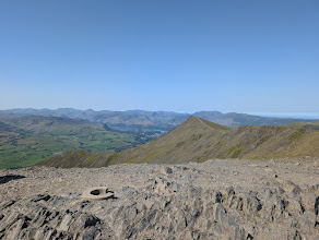 Blencathra - a rocky summit above a green valley and lake, a wide sweep of distant fells beyond