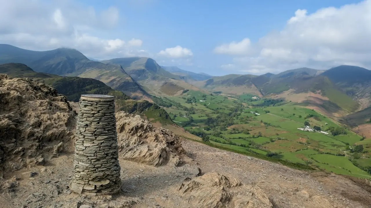 Catbells - a conical drystone column on the rocky summit, the green Newlands Valley and its farms spread below
