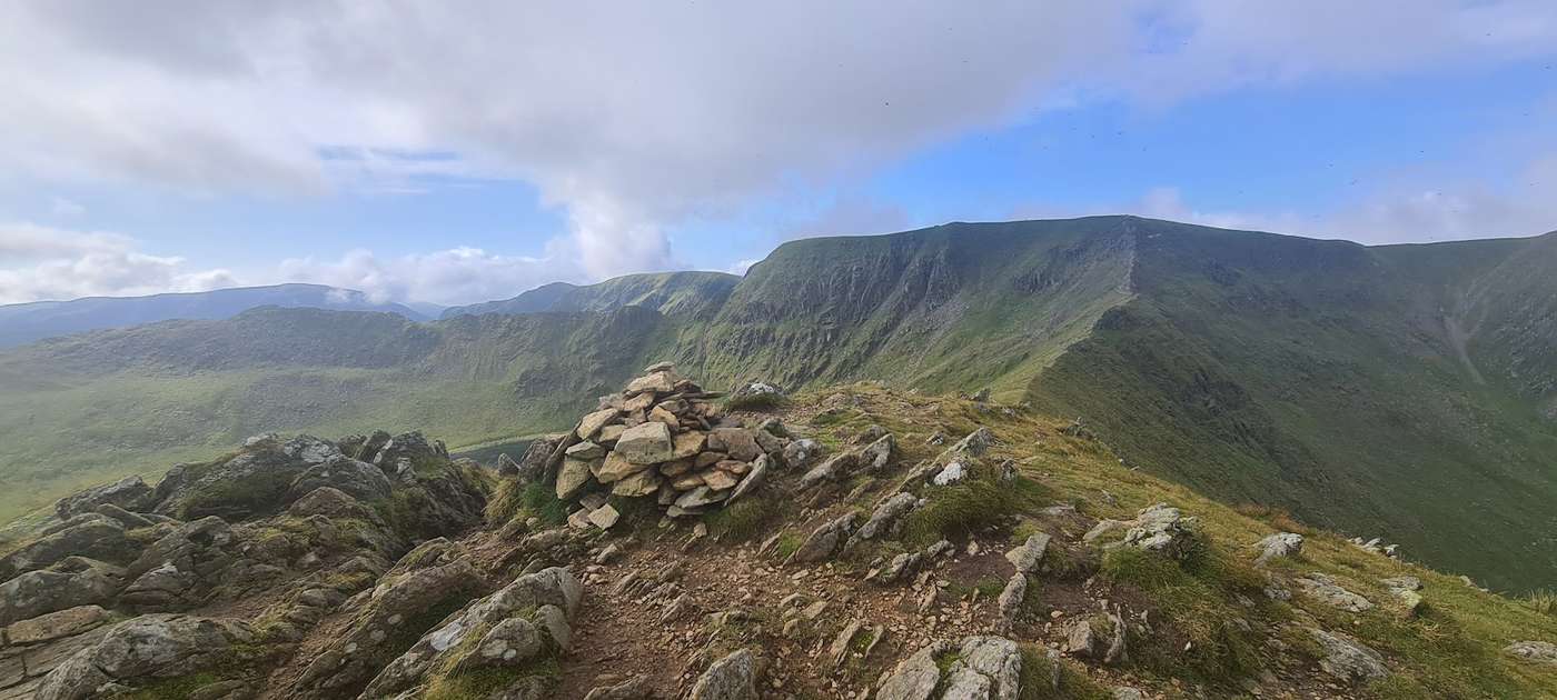 Catstye Cam - a low cairn on the stony top, the craggy ridge and coves of Helvellyn rising opposite