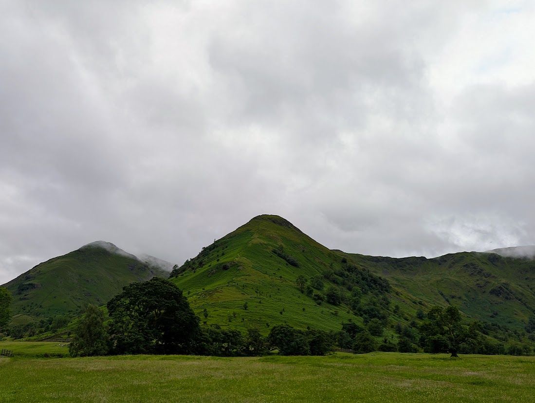 High Hartsop Dodd - a small stone cairn on a grassy top, a green valley dropping to Brothers Water among the fells