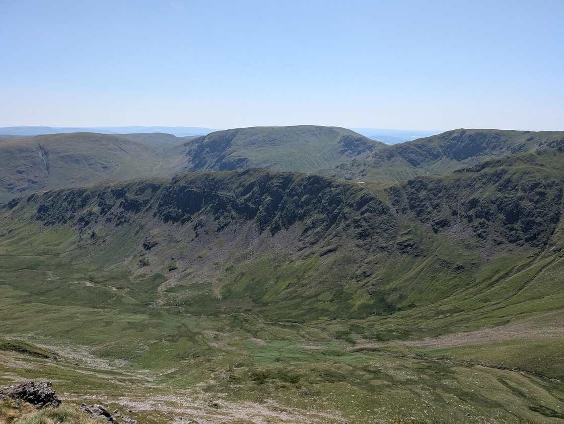 Kidsty Pike - broad grassy fells with steep crag-rimmed coves across a deep green valley, under clear blue sky