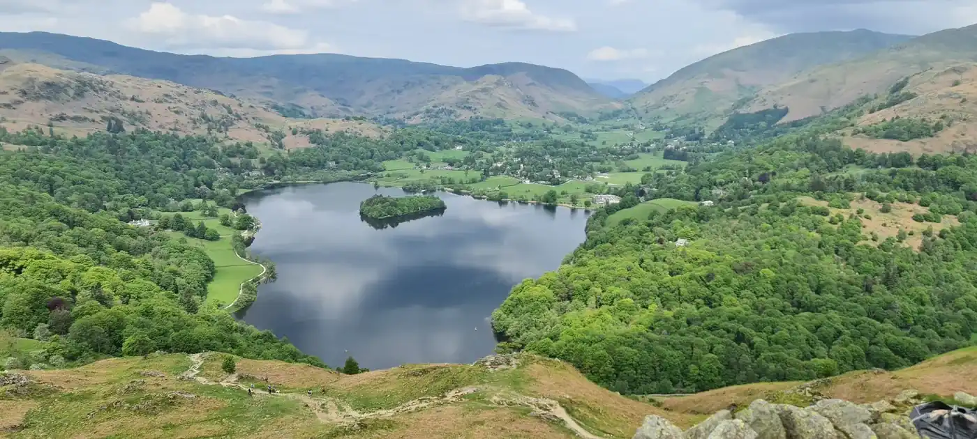 Loughrigg Fell - a green wooded view down over Grasmere lake and its island, the village and valley beyond