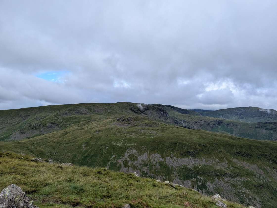 Middle Dodd - a grassy top looking across to the broad green bulk of higher fells, low cloud brushing the tops