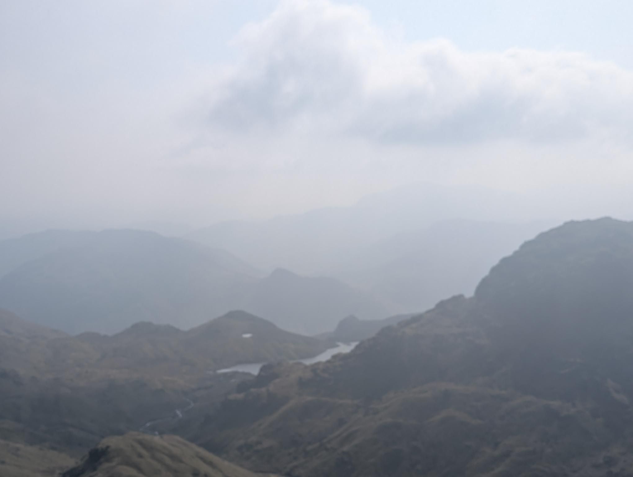 Sergeant Man - hazy layered fells fading into the distance, a tarn and winding beck in the valley far below
