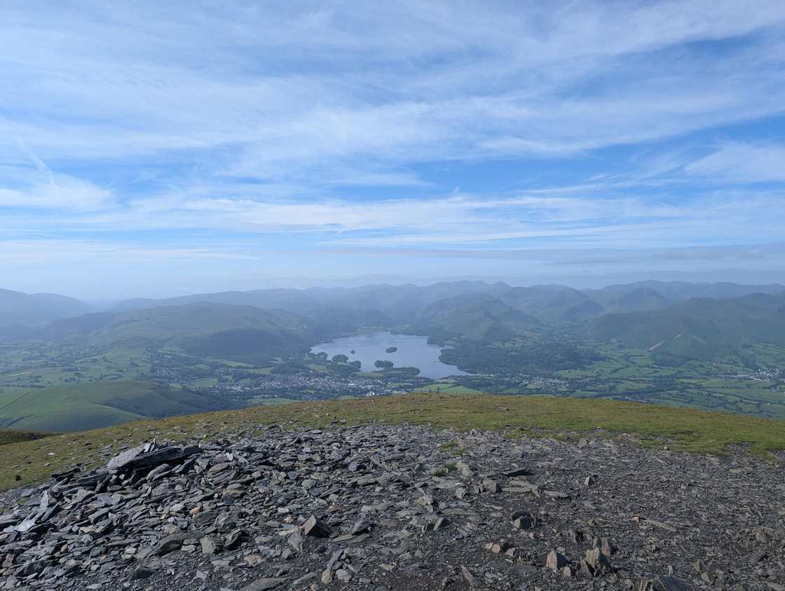 Skiddaw Little Man - a stony top looking down over Keswick and Derwentwater, hazy fells ringing the lake under blue sky