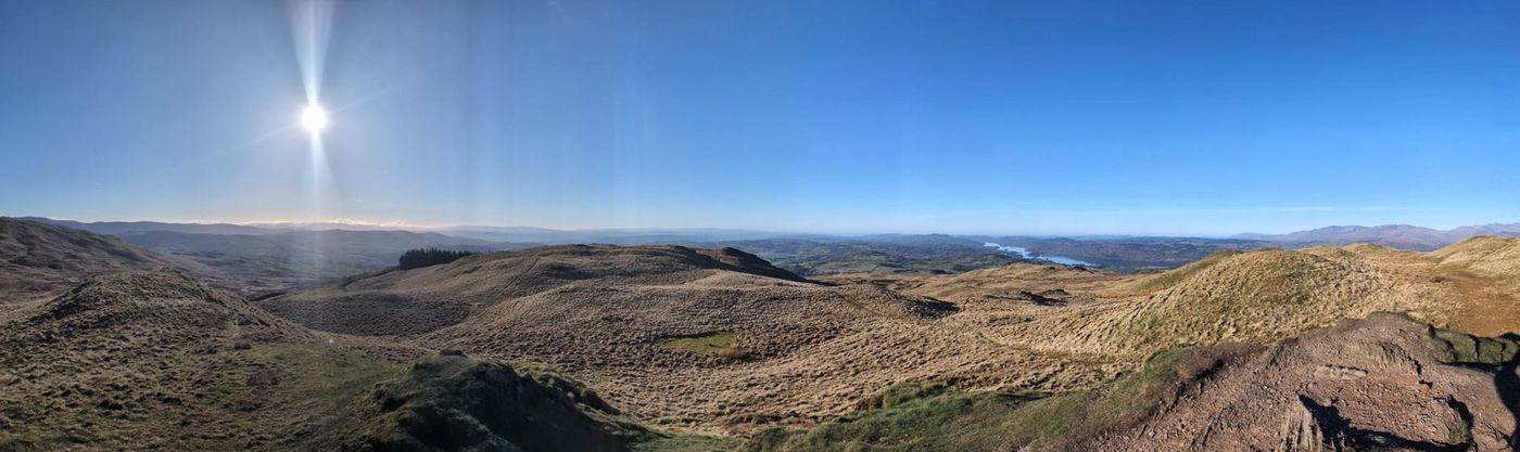 Sour Howes - a wide panorama of brown grassy moorland, the low sun to one side and Windermere glinting in the distance