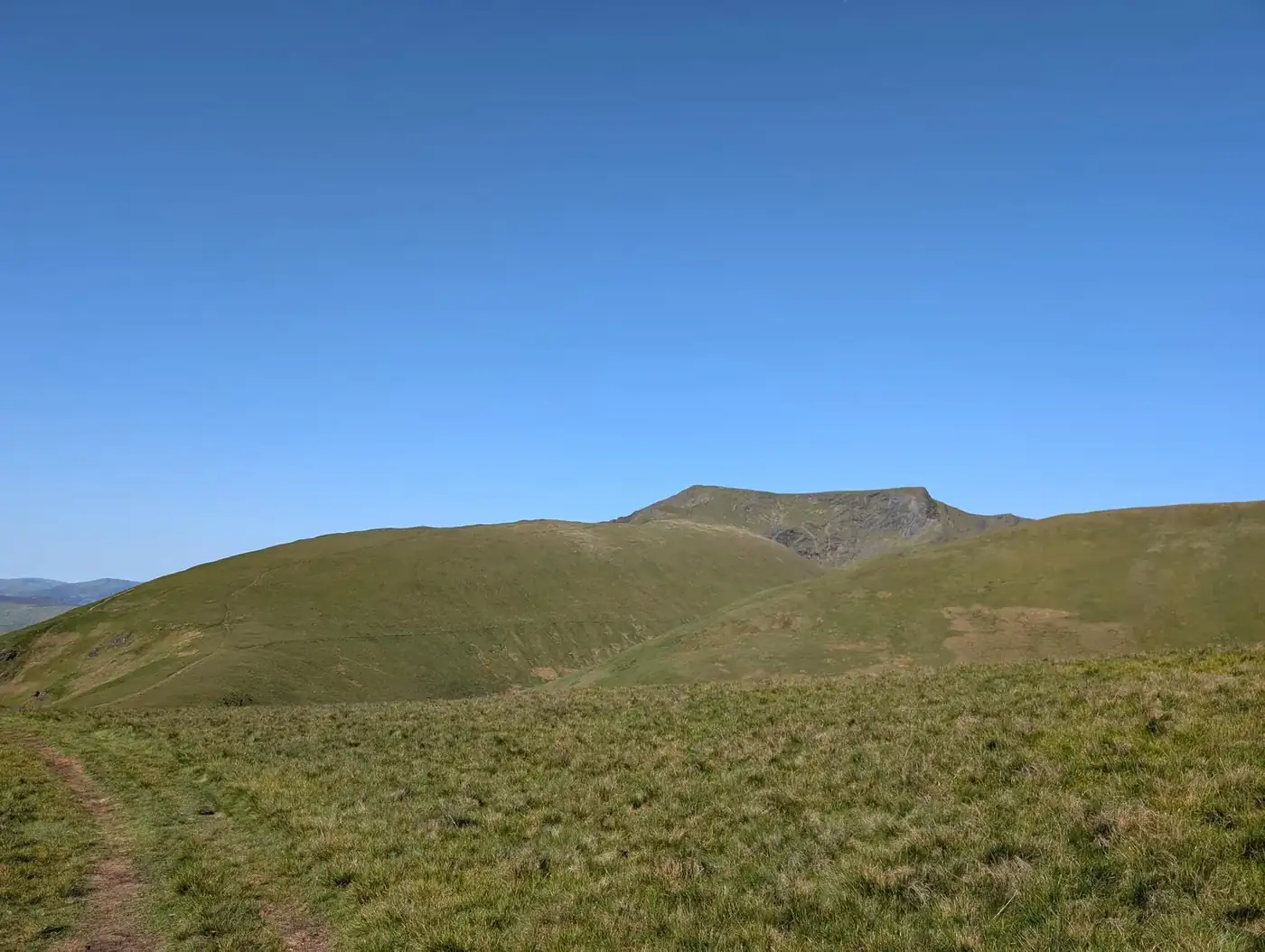 Souther Fell - a grassy path looking across to the broad green bulk of Blencathra under a clear deep-blue sky