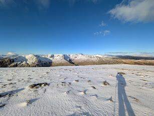 St Sunday Crag - a snow-covered summit looking across to a panorama of snow-capped fells under a bright blue sky