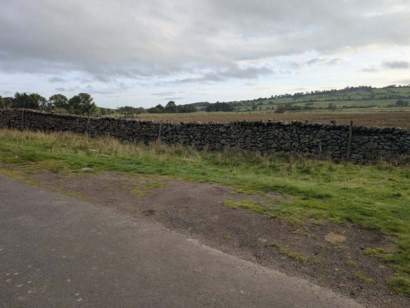 A wide gravel verge beside a drystone wall