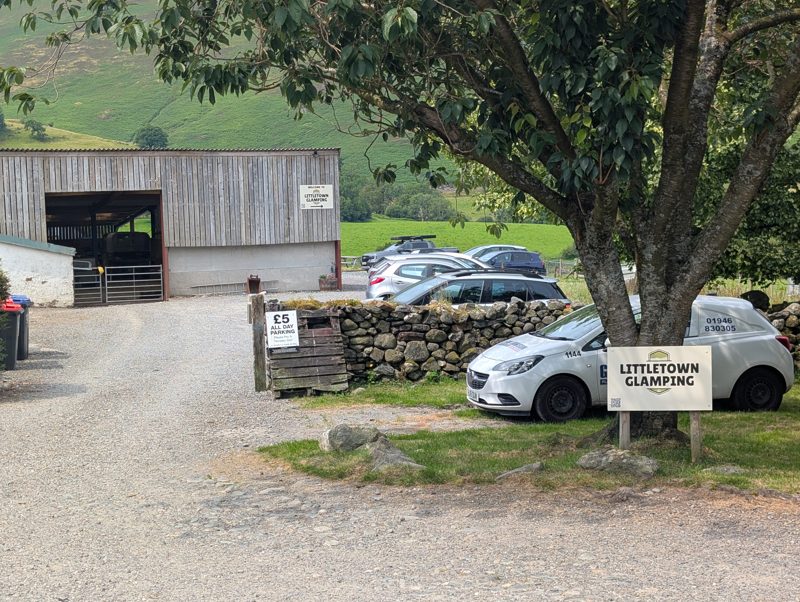 Farm track at Littletown in Newlands, with a hand-painted sign for all-day parking at five pounds beside Littletown Glamping