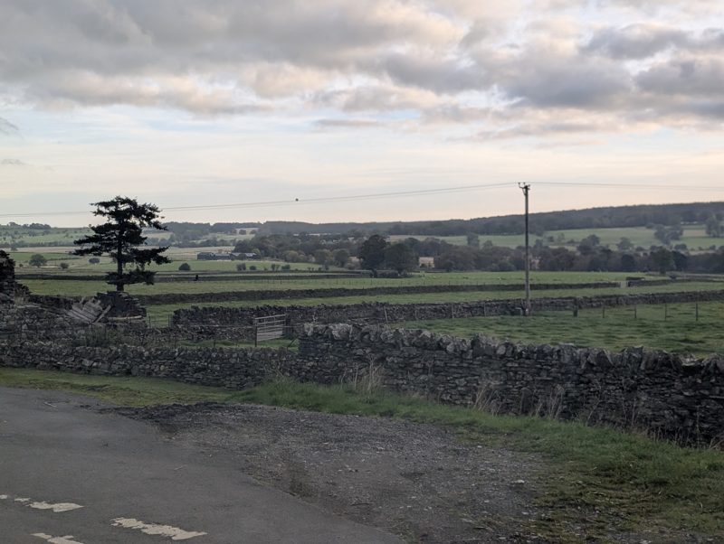 A rough pull-in beside a drystone wall, with fields beyond