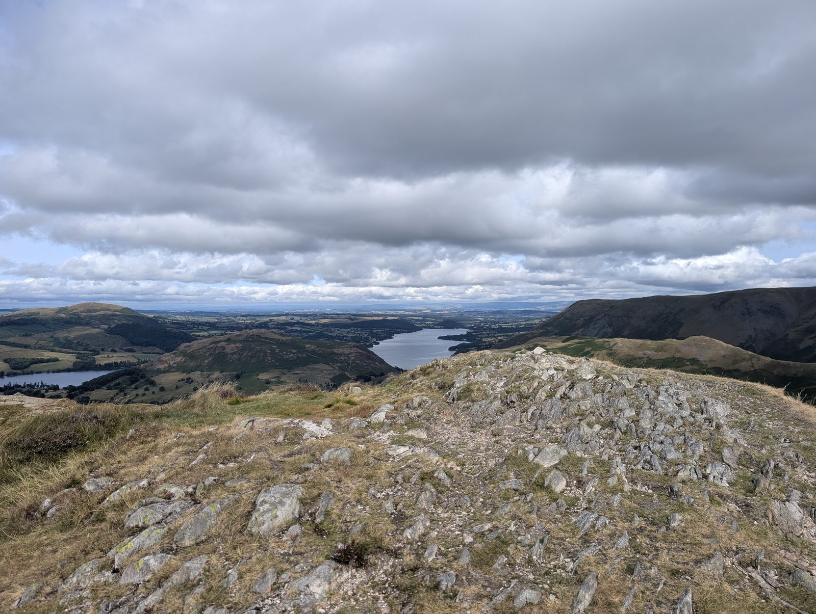 A rocky knoll on the climb from Beda Fell towards Place Fell, with water glinting in the valley below
