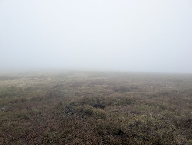 Featureless grass and heather moor fading into mist on the way to Miton Hill
