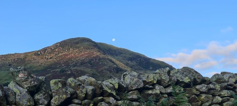 Ullswater winding away between steep fellsides, with Glenridding's fields and rooftops on the valley floor far below