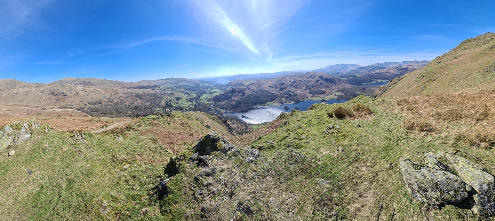Looking down from the rocky spine of Nab Scar over Rydal Water and Grasmere in the valley below, with wooded slopes and range after range of fells beyond